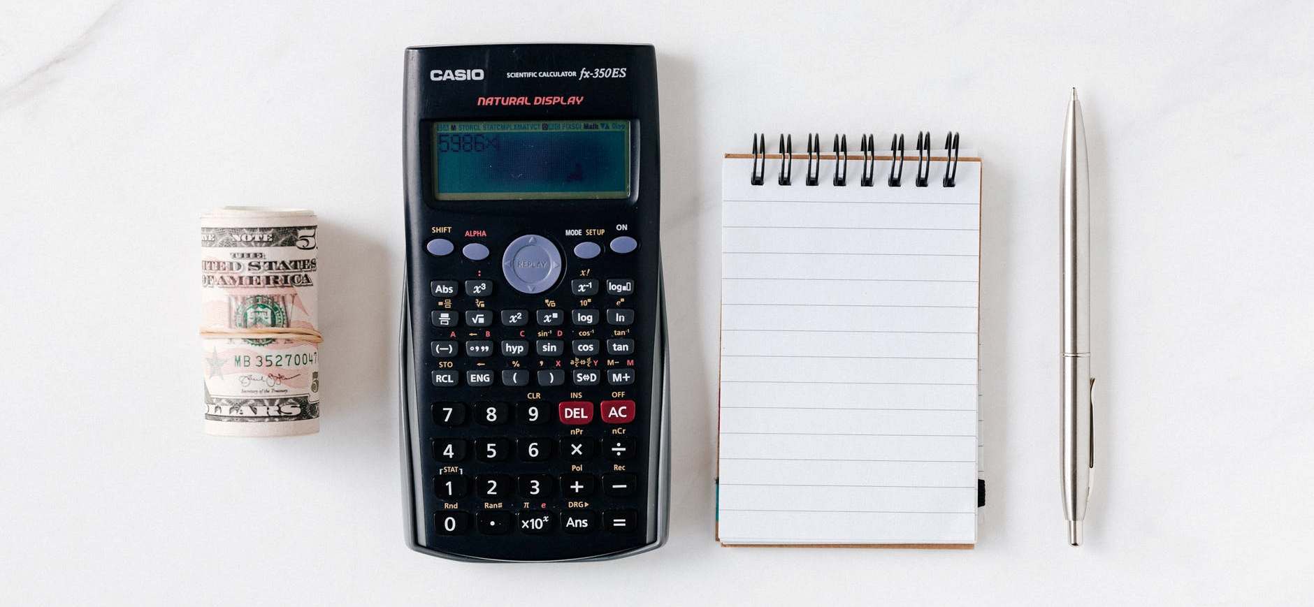 a calculator, stack of money and a notebook