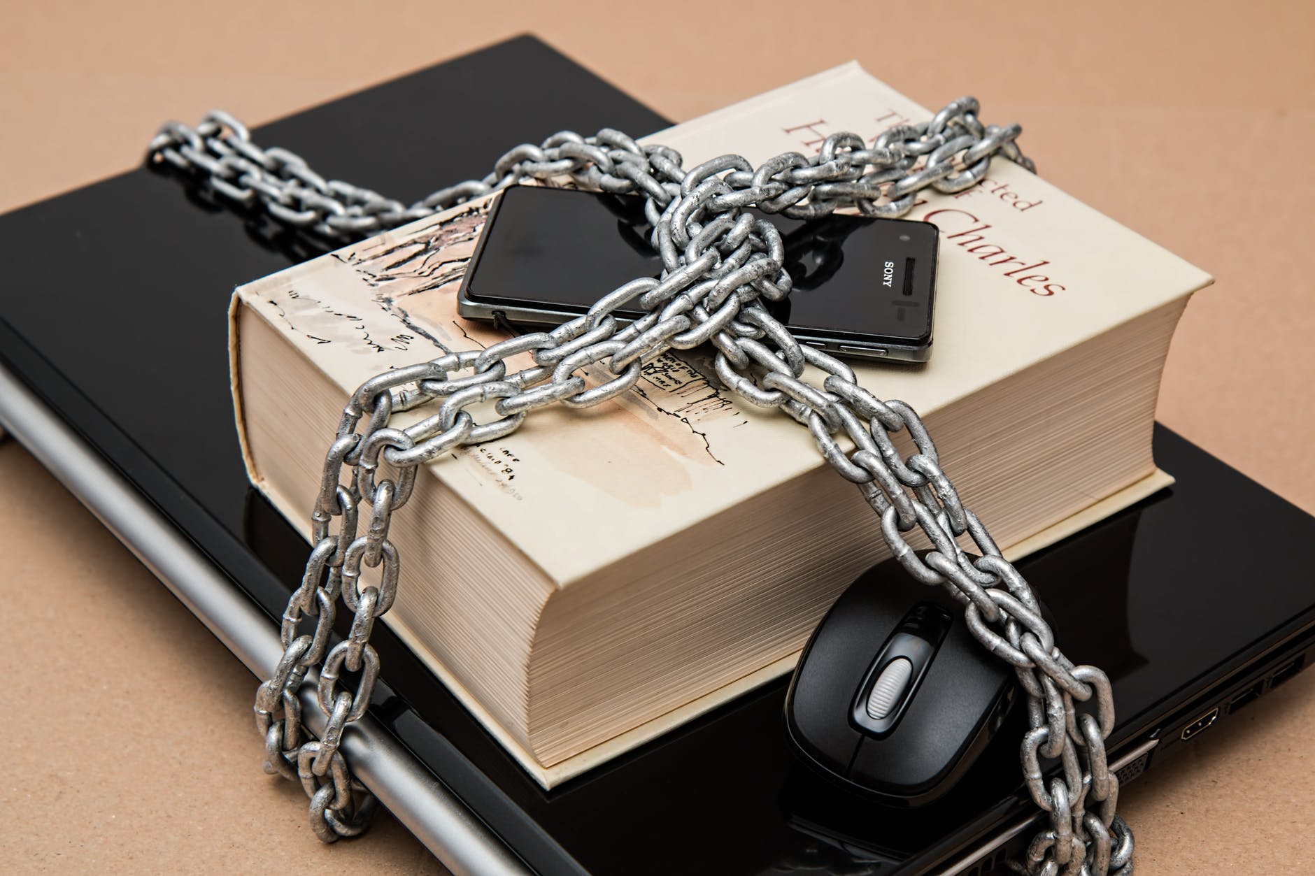 laptop, a book an a mobile phone in chains