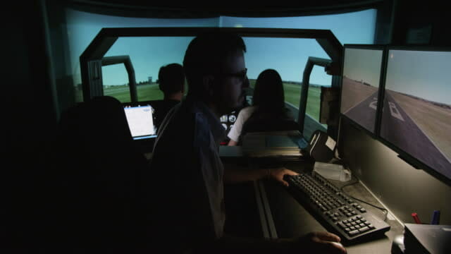 Man in a dark room looking at a monitor with an airport 