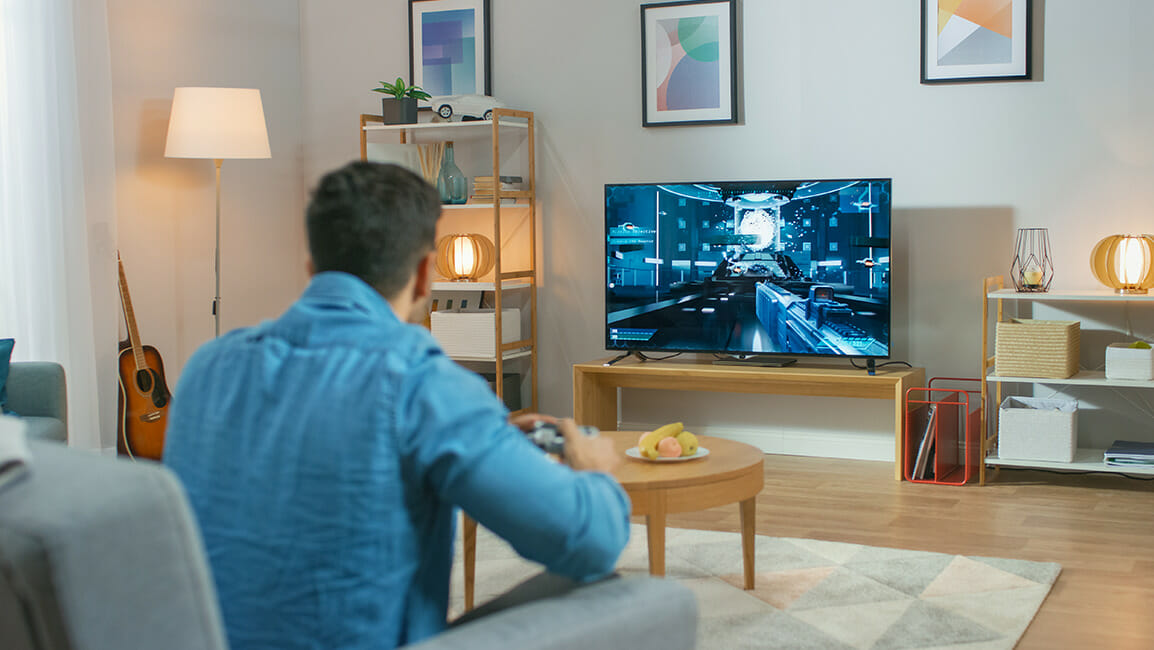 Man in a lue shirt playing a game on a TV