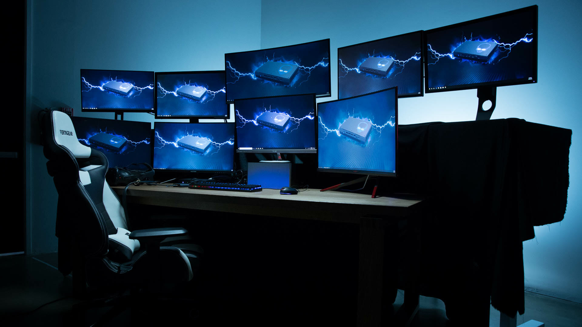 Many monitors on a table in a dark room