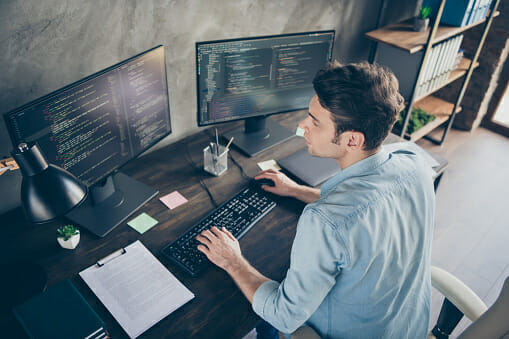 A man programming on a monitor