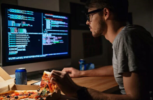 a man eating pizza in front of the monitor