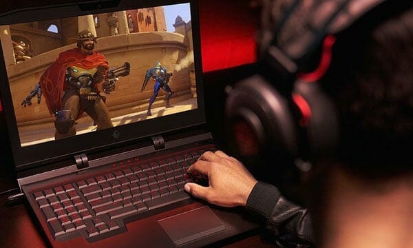 A guy with headphones gaming on a laptop