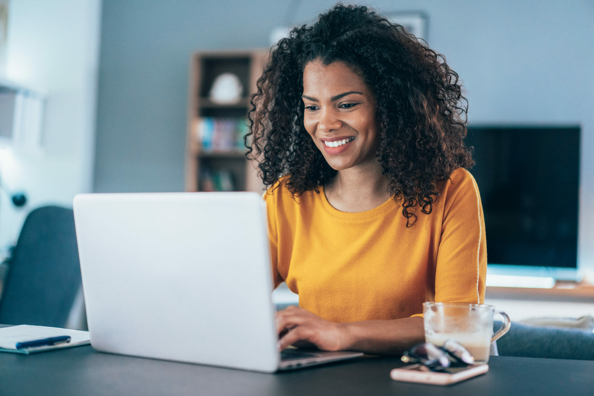 Woman with curly hair smiling on a laptop