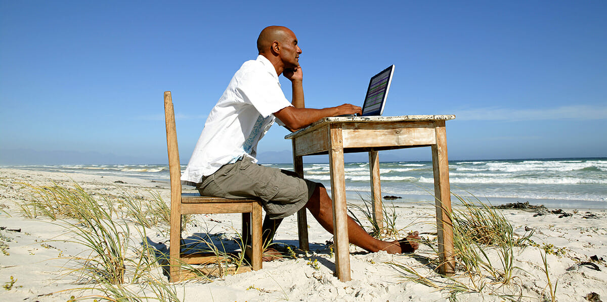 A man on a beach with a laptop