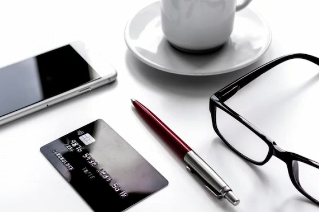 a credit card, a pen, glasses and cell phone on the table