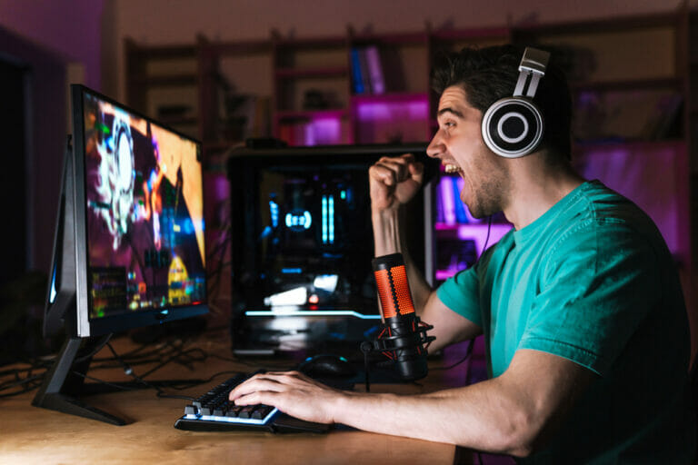 A man playing games on a monitor with his headphones on