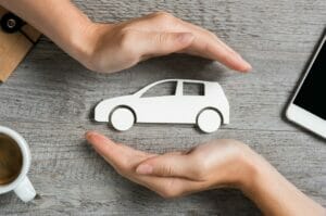 Hands protecting a paper car