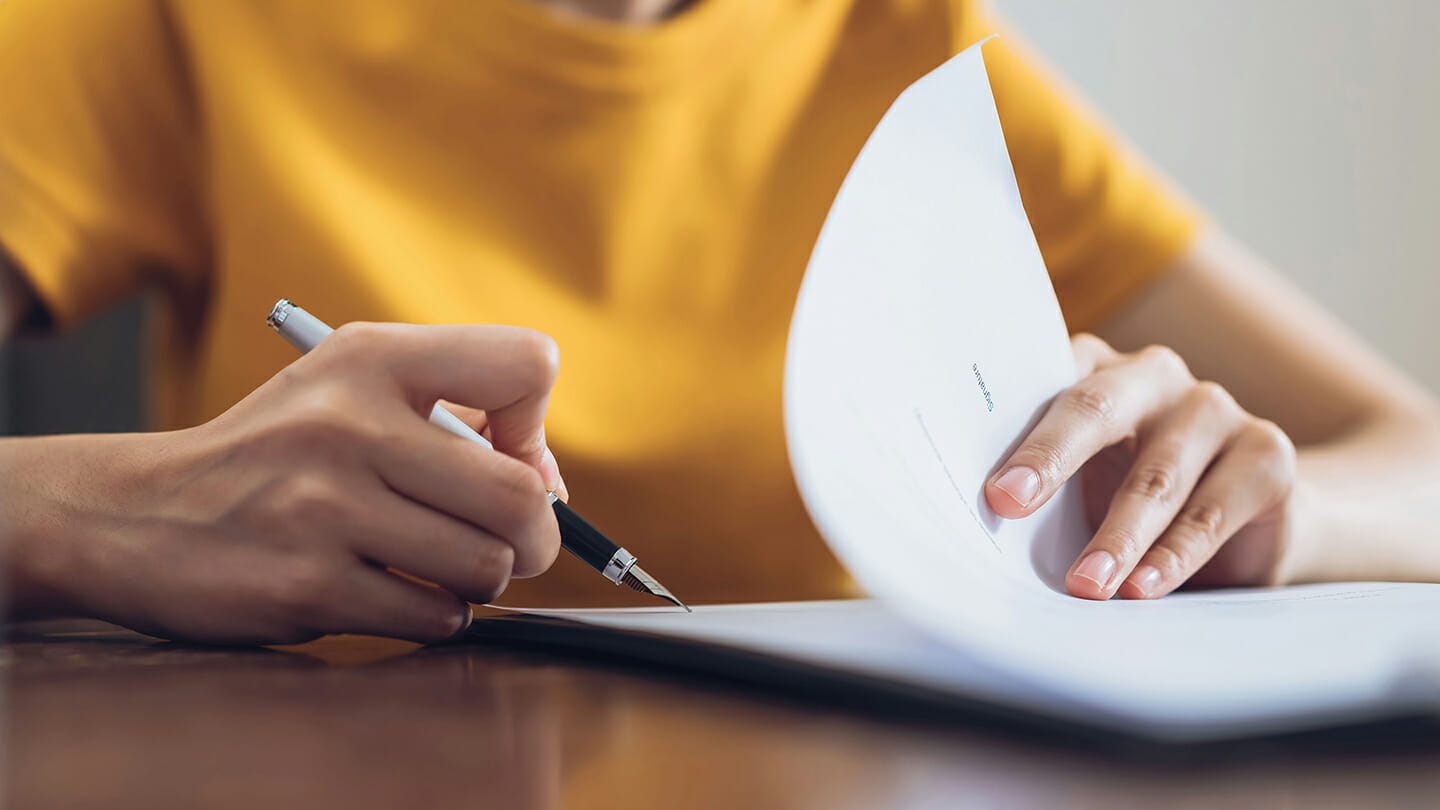 Woman in yellow signing a document