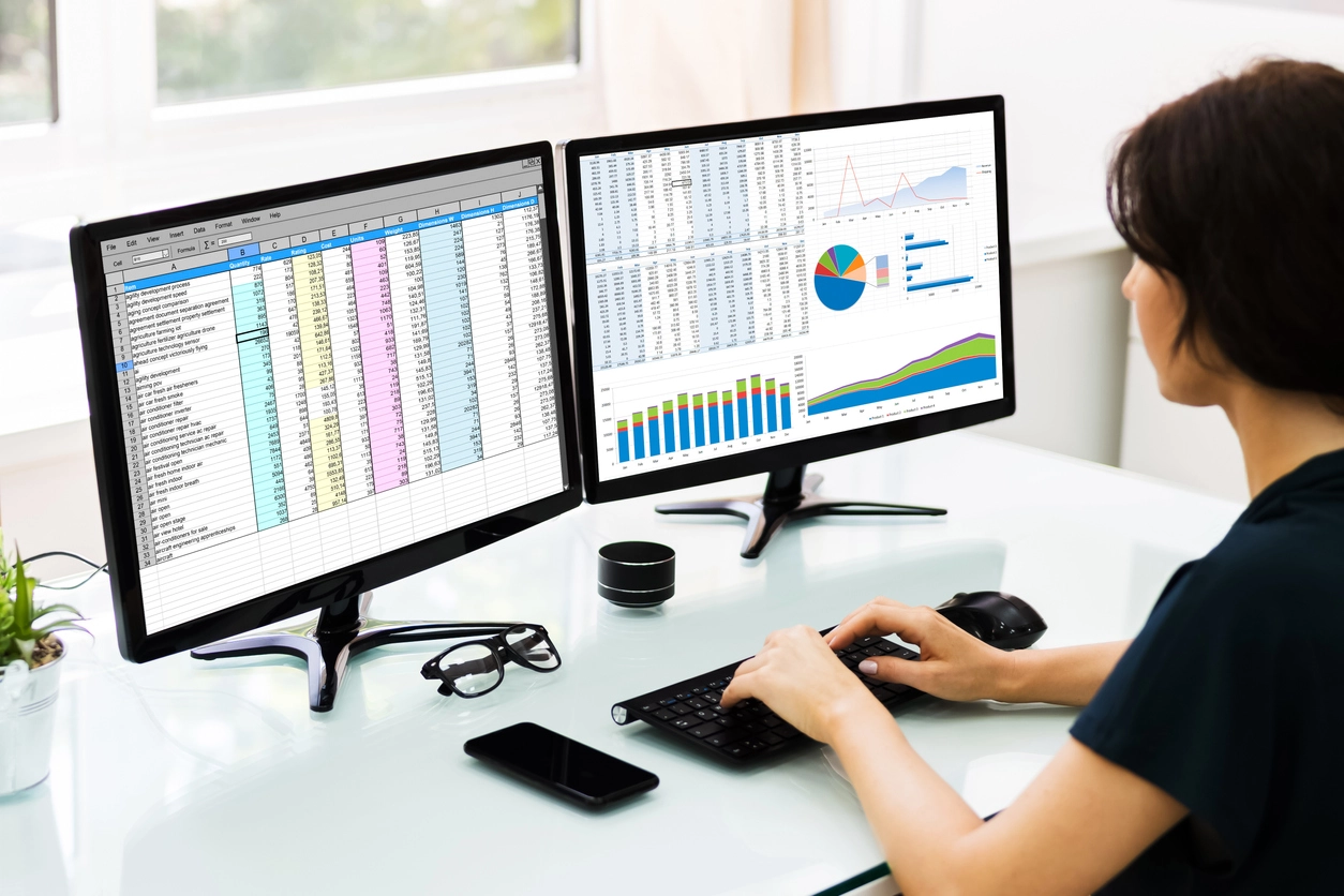 Excel opened on a double monitor, woman working in it
