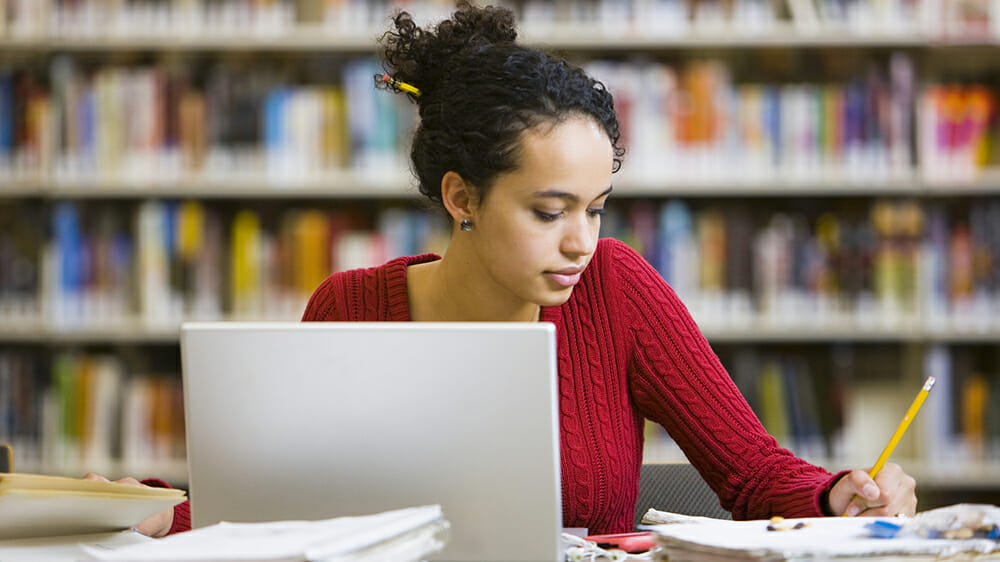 Girl in a library with a laptop